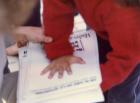 Un niño coloca su mano sobre una de las hojas afiches para que sea silueteada sobre él. 