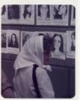 Perfil de Madre con pañuelo frente a muro con fotocopias con imágenes de mujeres desaparecidas. 