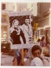 Madre de Plaza de Mayo con estandarte con imagen de pareja de desaparecidos cuyo hijo nació en cautiverio 